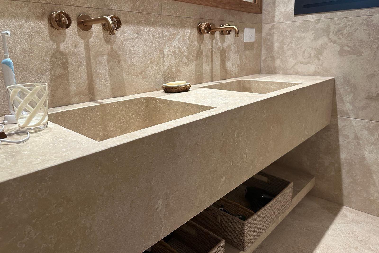 Top bagno sospeso in travertino con due lavabi, montato in un bagno