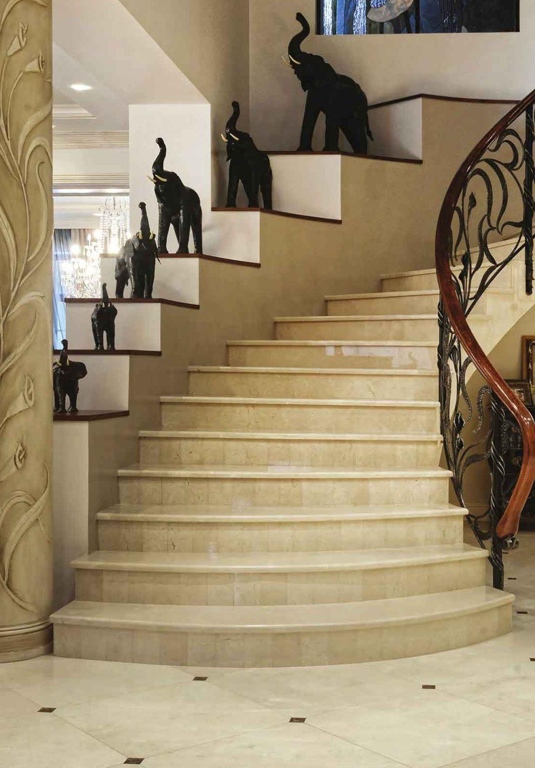 Scala curva con gradini in marmo crema e ringhiera in ferro