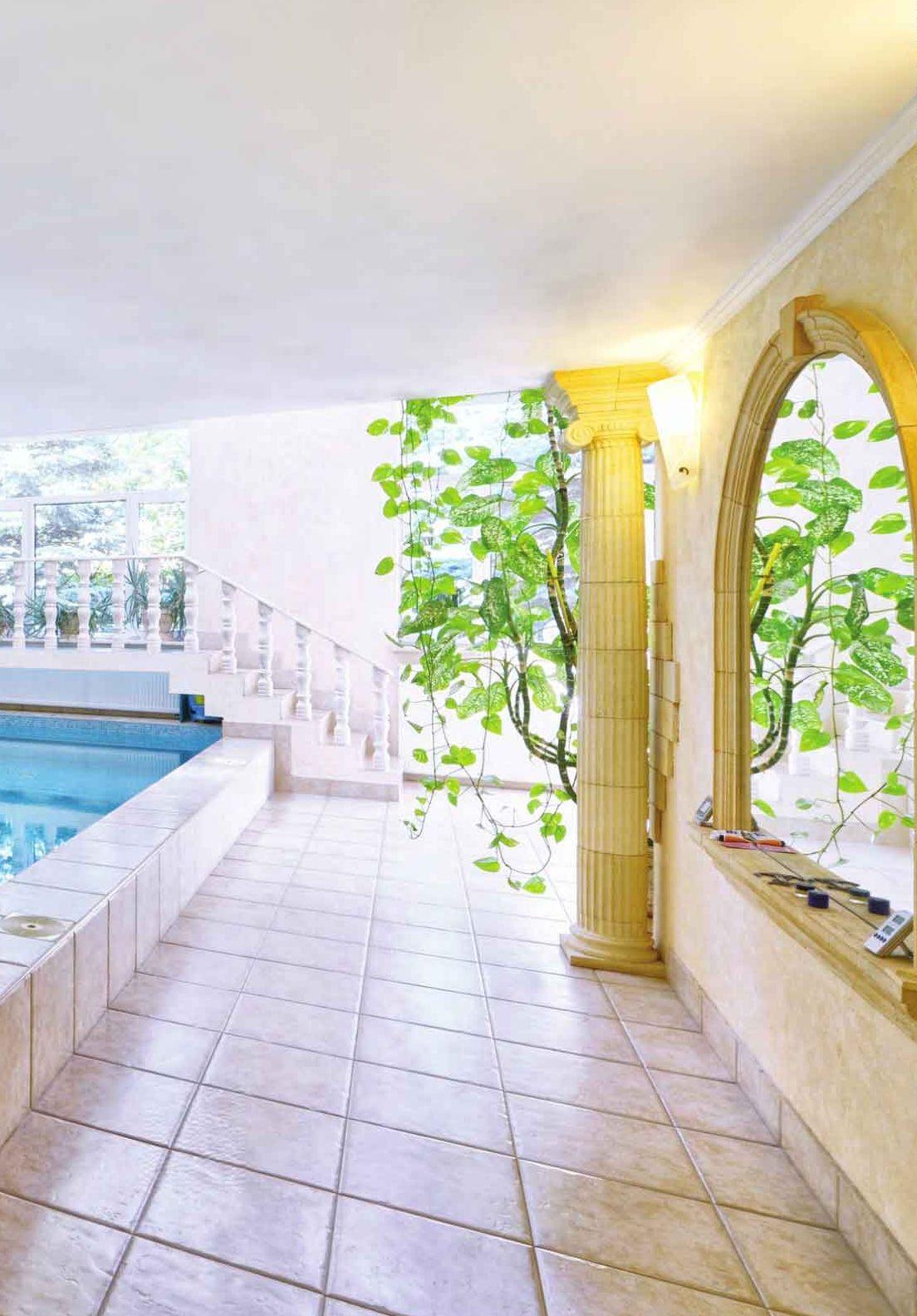 Portico con pavimento in pietra, archi e colonne verso la piscina