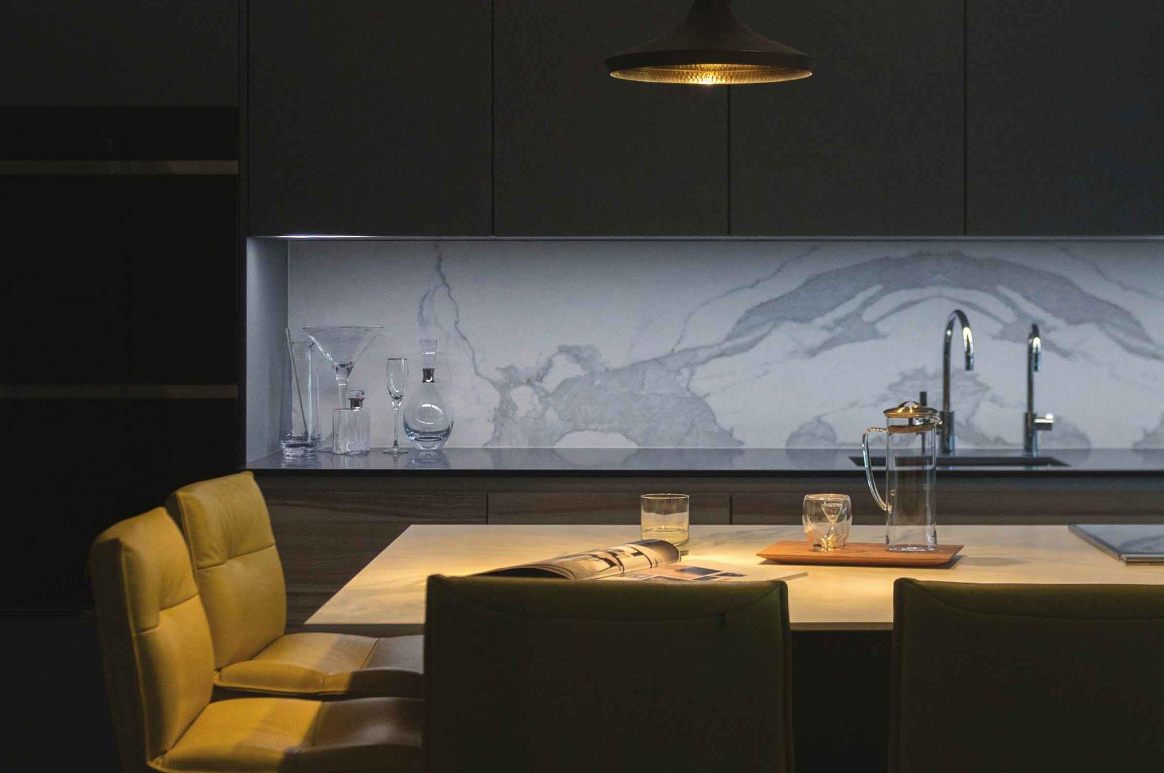 Cucina scura con retrobanco in marmo venato retroilluminato