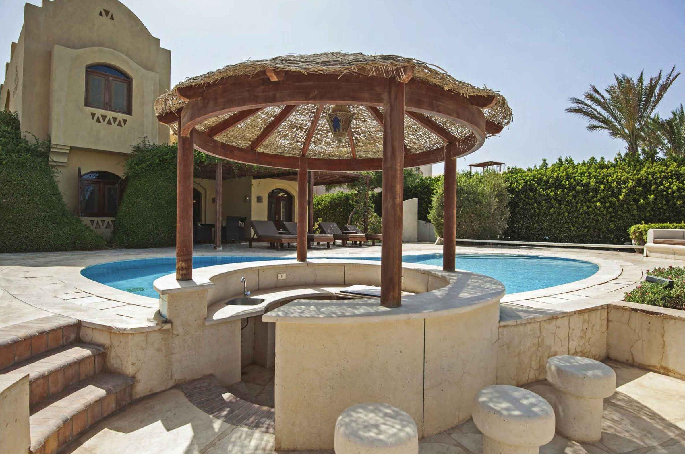 Piscina esterna con bordo in pietra, sedute e pergola