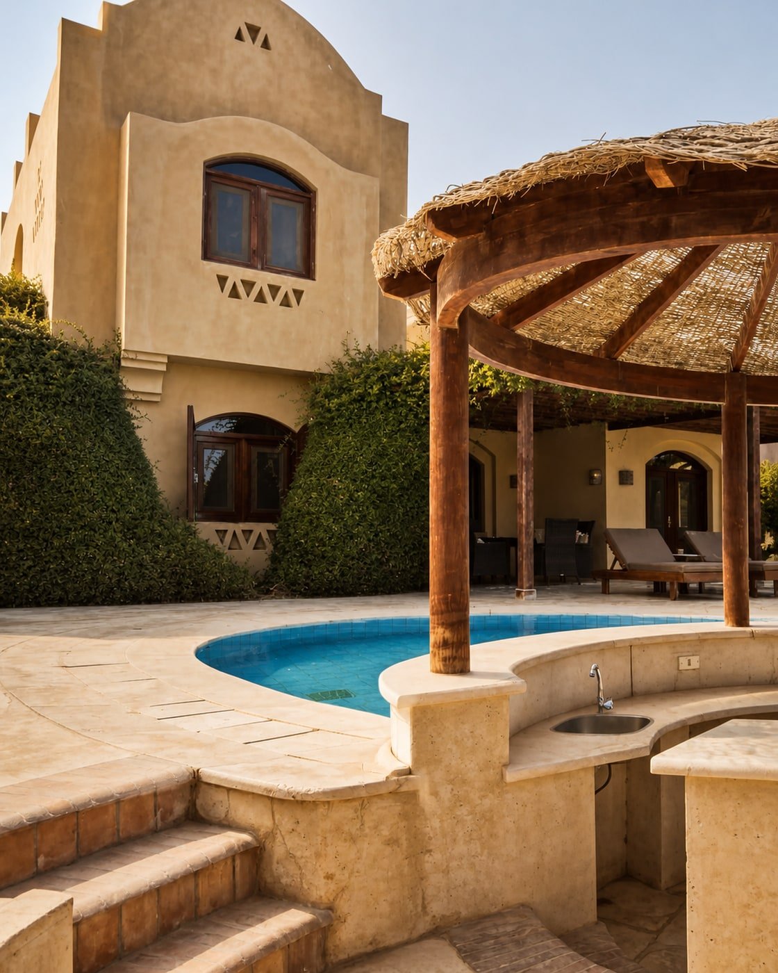 Bar in pietra con lavello integrato, pergola circolare e gradini accanto alla piscina