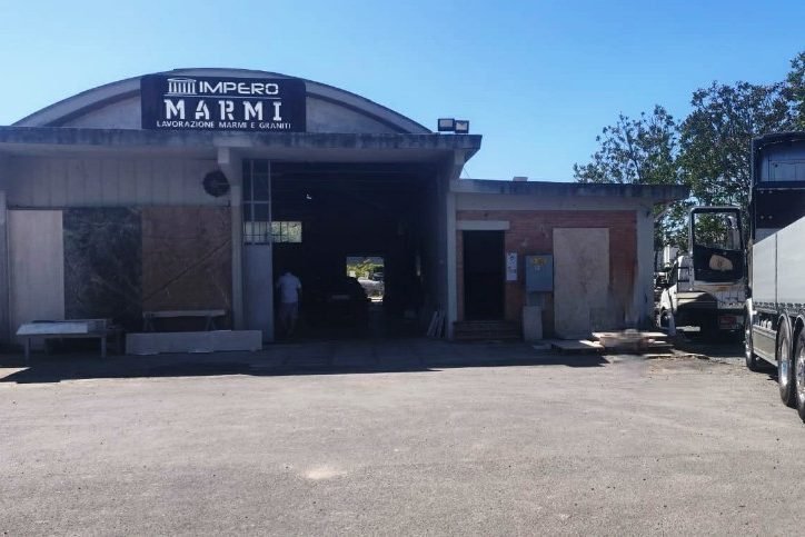 La facciata del laboratorio Impero Marmi con l'insegna, vista dal piazzale