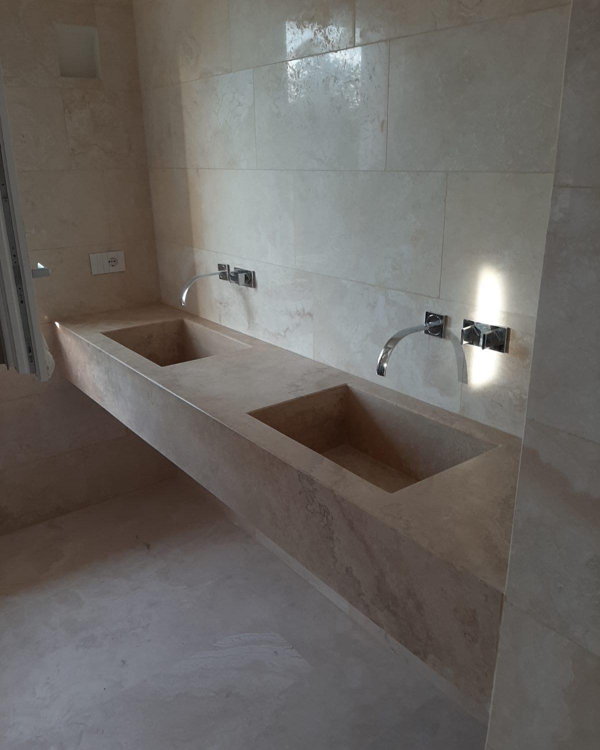 Doppio lavabo in travertino ricavato dal pieno, con rivestimento a parete