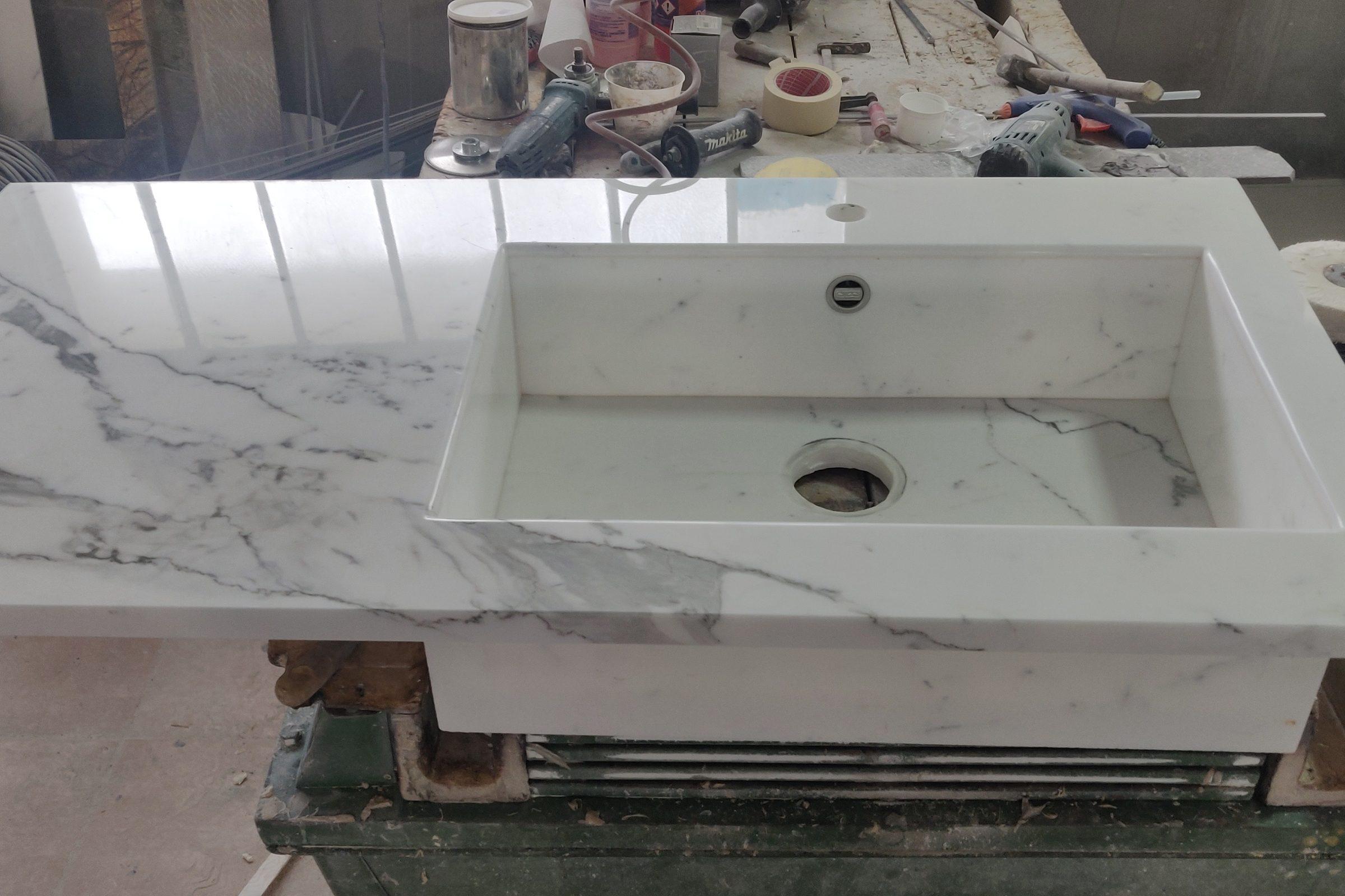Lavabo in marmo bianco venato scavato nel pieno, sul banco del laboratorio