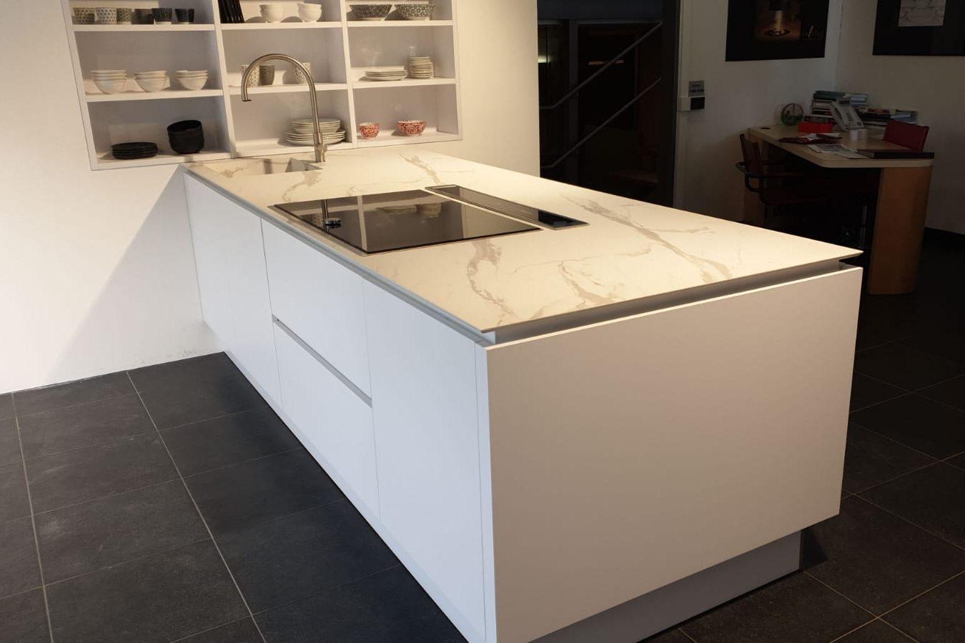 Isola cucina con piano in pietra bianca venata e piano cottura a filo